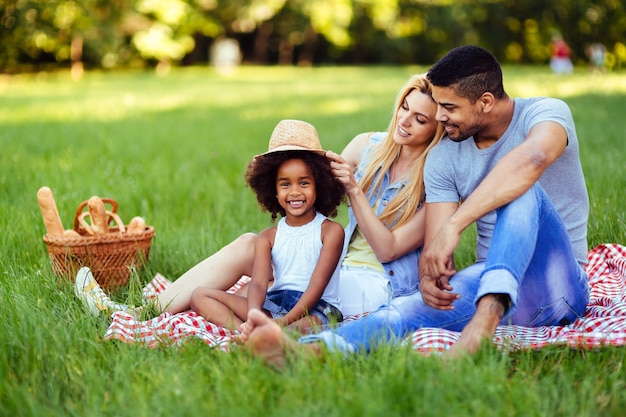 Imagen de la encantadora pareja con su hija haciendo un picnic en la naturaleza