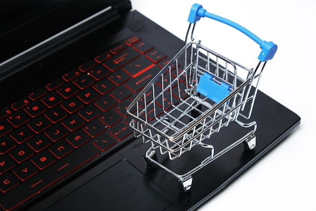 Imagen de enfoque selectivo del carrito de juguete con información de computadora portátil para el concepto de compras en línea Las compras en línea son ahora una tendencia durante el brote de Covid19