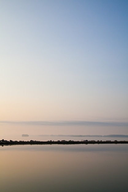 Imagen de la escena del lago pacífico donde un afloramiento rocoso se refleja en las aguas tranquilas