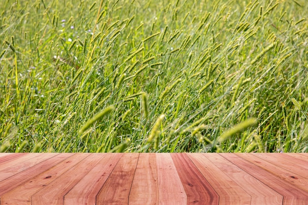 Una imagen de un escritorio de madera delante de un fondo abstracto de una flor de la hierba.