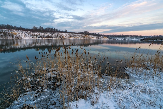 Una imagen especular del cielo y la costa con una capa de nieve en el embalse