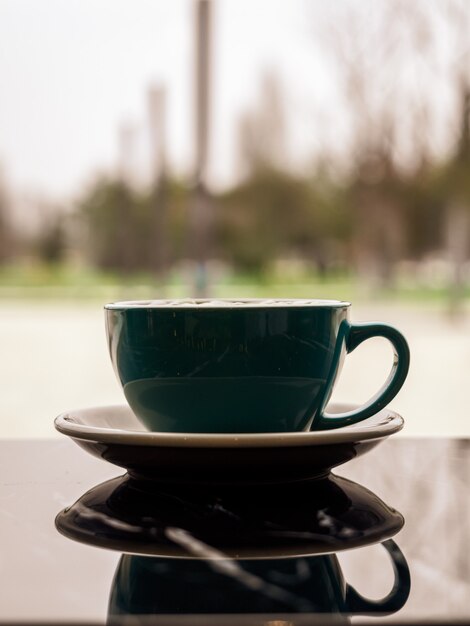 Imagen de espejo de una hermosa taza elegante en la superficie oscura de la mesa