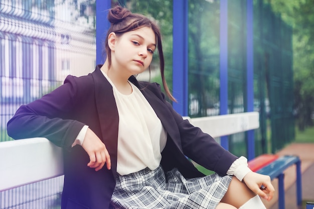 Imagen de estilo de película de ruido artístico. Retrato de colegiala de trece años con blusa blanca, falda a cuadros y chaqueta en la escuela. Chica adolescente emocional posando mirando a la cámara. Concepto de edad escolar y aprendizaje.