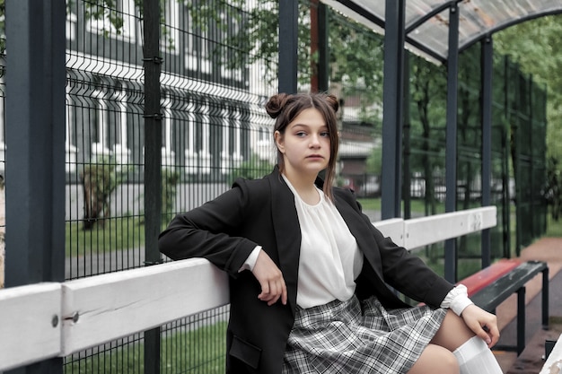 Imagen de estilo de película de ruido artístico. Retrato de colegiala de trece años con blusa blanca, falda a cuadros y chaqueta en la escuela. Chica adolescente emocional posando mirando a la cámara. Concepto de edad escolar y aprendizaje.