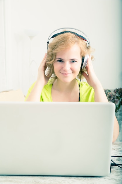 Imagen de estilo retro de una mujer escuchando música frente a una computadora portátil