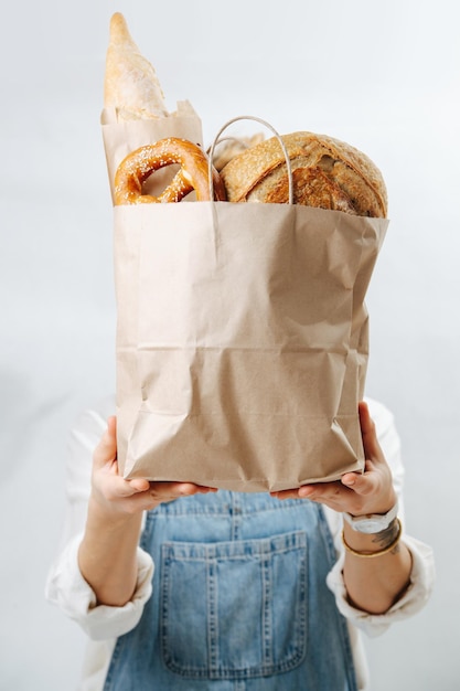 Sin imagen facial de una mujer sosteniendo una bolsa de papel llena de pastelería dorada