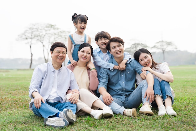 Imagen de una familia asiática sentada en el césped del parque