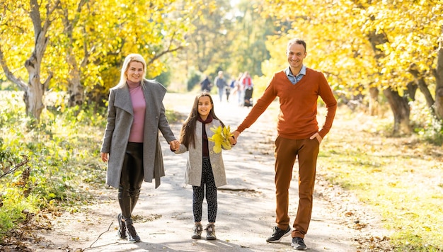 Imagen de una familia encantadora en el parque de otoño, padres jóvenes con un niño adorable y agradable jugando al aire libre, diviértanse en el patio trasero en otoño, la familia feliz disfruta de la naturaleza otoñal.