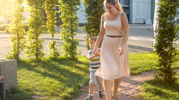 Imagen de feliz madre joven con hijo de 3 años jugando y corriendo en el parque infantil en el parque