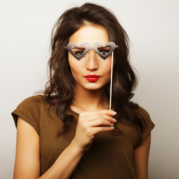 Imagen de fiesta Mujer joven juguetona sosteniendo unas gafas de fiesta Listo para pasar un buen rato