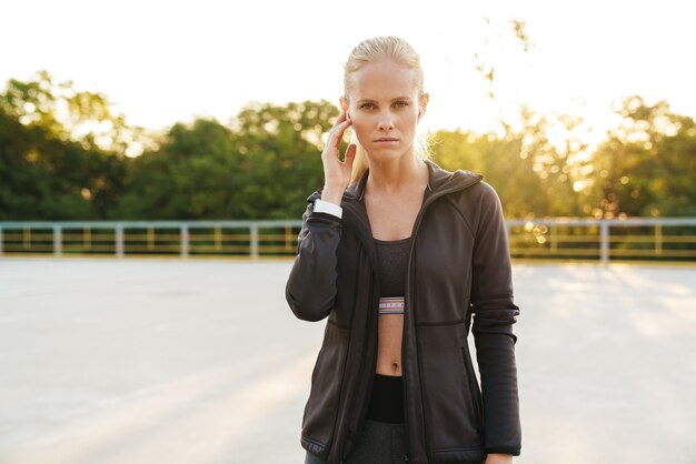 Imagen de fitness deportista vistiendo chándal y earpods caminando al aire libre