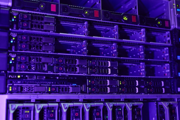 Imagen de fondo futurista de servidores en rack en una red de supercomputadoras iluminada por luz azul y violeta, espacio de copia