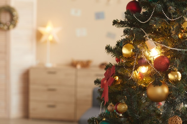 Imagen de fondo del hermoso árbol de Navidad decorado con baulbs dorados en el acogedor interior de una casa, espacio de copia