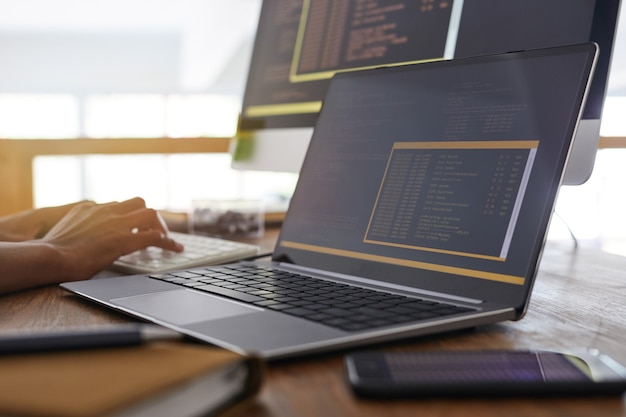 Foto imagen de fondo de manos masculinas escribiendo en el teclado con código de programación negro y naranja en la pantalla del portátil en primer plano, concepto de desarrollador de ti, espacio de copia