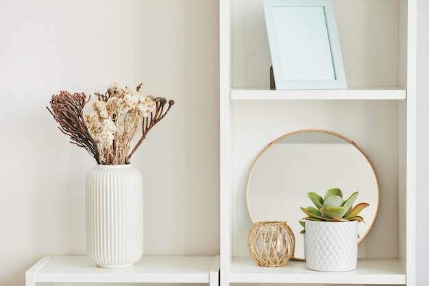 Imagen de fondo mínima de elegantes accesorios de decoración para el hogar en estante blanco con plantas, espacio de copia