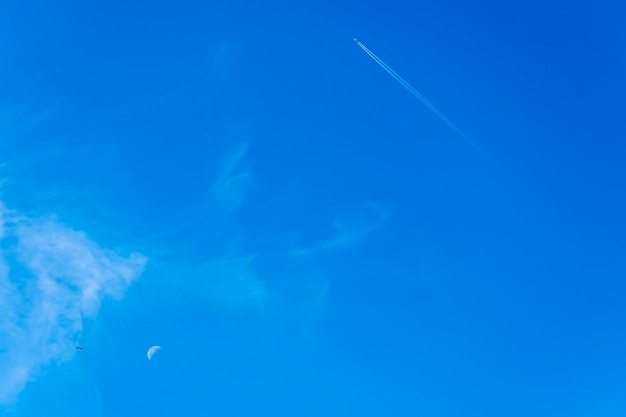 Imagen en formato vertical de una media luna distante aislada en un cielo azul