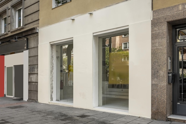 Imagen frontal de la fachada de un local comercial a pie de calle con paredes revestidas con paneles metálicos y cristal oscuro