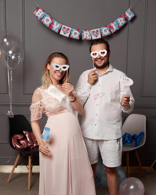 Imagen frontal de una pareja sonriente con inscripción niño o niña y máscara en la cara durante la fiesta de revelación de género