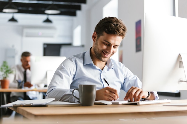 Imagen del gerente masculino sonriente escribiendo algo