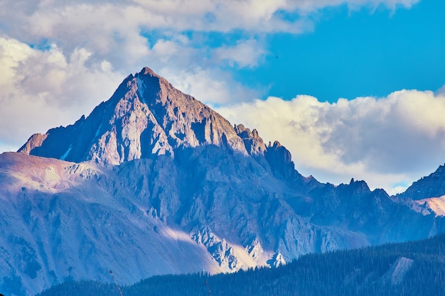 Imagen de gran montaña rocosa con nieve y rayos de sol