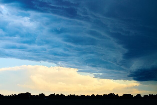 Imagen de grandes nubes de tormenta sobre la silueta de bosques y tierras de cultivo