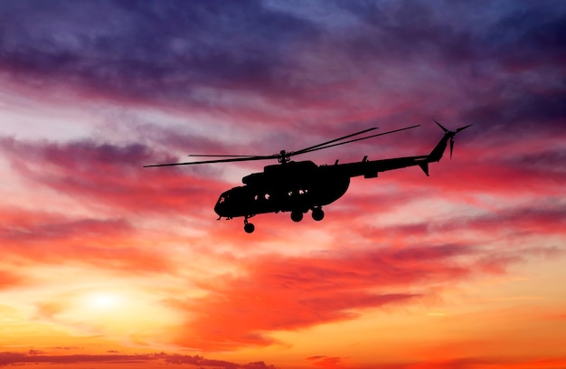 Imagen de helicóptero al atardecer. Silueta de helicóptero en el cielo del atardecer.