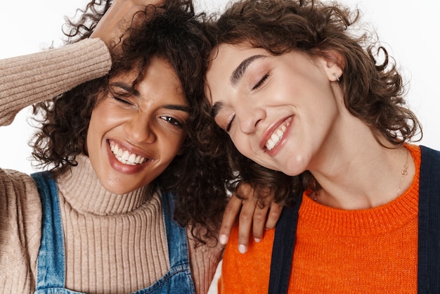 Imagen de una hermosa feliz alegre optimista dos amigas multirraciales en monos de mezclilla