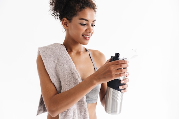 Imagen de una hermosa joven mujer africana de fitness deportes asombrosos agua potable sosteniendo una toalla.