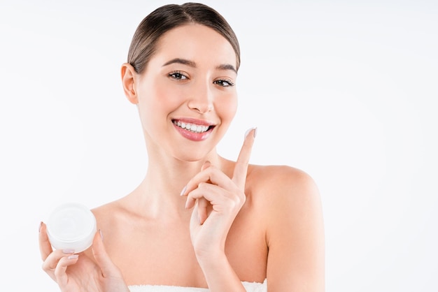 Imagen de una hermosa joven sosteniendo crema posando aislada sobre fondo blanco