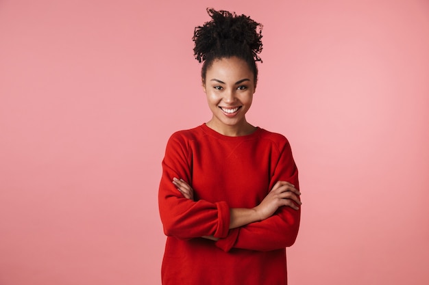 Imagen de una hermosa mujer africana riendo feliz increíble joven posando sobre pared rosa.