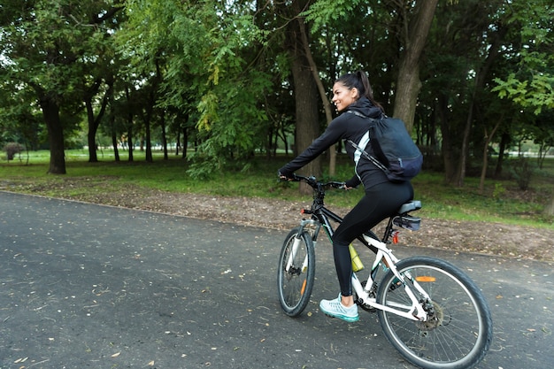 Imagen de una hermosa mujer caminando en bicicleta en el parque al aire libre.