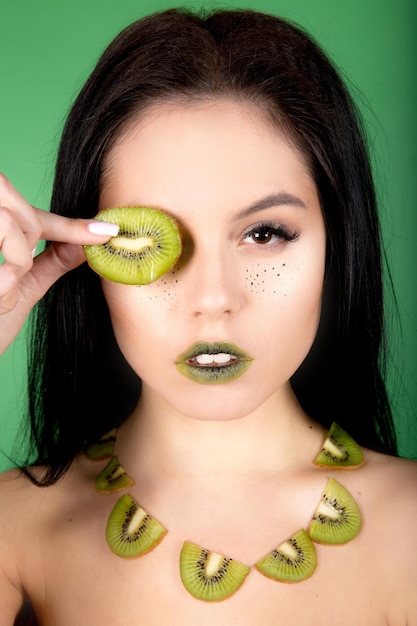 Imagen de hermosa mujer sin camisa posando con kiwi. foto creativa