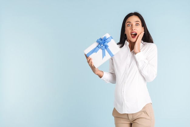 Imagen de una hermosa mujer embarazada joven sorprendida aislada con caja de regalo.