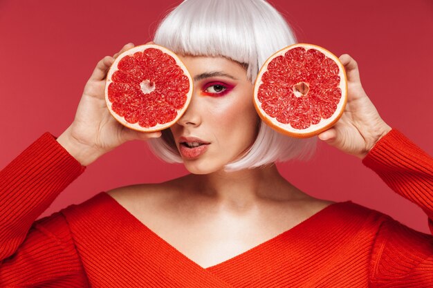 Imagen de hermosa mujer joven aislada en pared roja con pomelo.