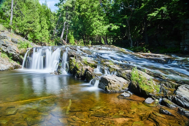 Imagen de hermosas cascadas en bosque verde sobre pendiente rocosa