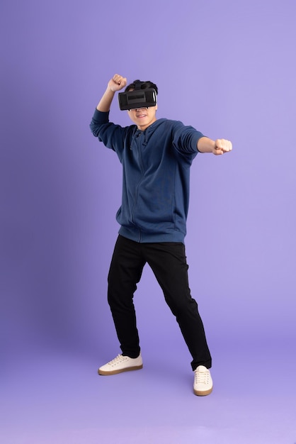 Imagen de un hombre asiático con gafas de realidad virtual sobre fondo morado