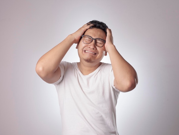 Imagen de un hombre asiático gracioso llorando cerrando los ojos triste depresión frustración expresión desesperada