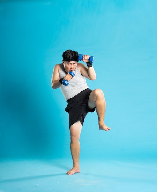 Imagen de un hombre asiático haciendo ejercicio sobre un fondo azul