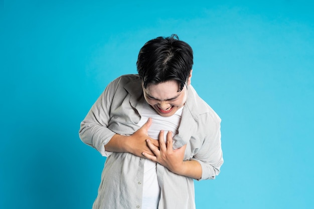 Foto imagen de un hombre asiático con problemas de salud aislado en fondo azul