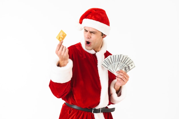 Imagen de hombre caucásico de 30 años en traje de santa claus con billetes de un dólar y tarjeta de crédito