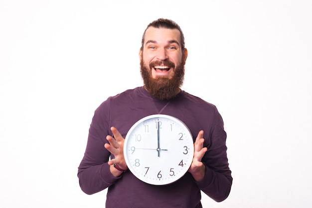 La imagen de un hombre emocionado sosteniendo un reloj está sonriendo