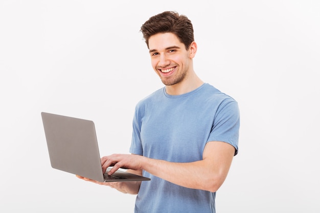 Imagen de hombre guapo en camiseta casual con cuaderno de plata y charlando o trabajando, aislado sobre la pared blanca