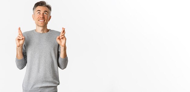 Foto imagen de un hombre de mediana edad emocionado y esperanzado haciendo un deseo rogando a dios que cruce los dedos para buena suerte y