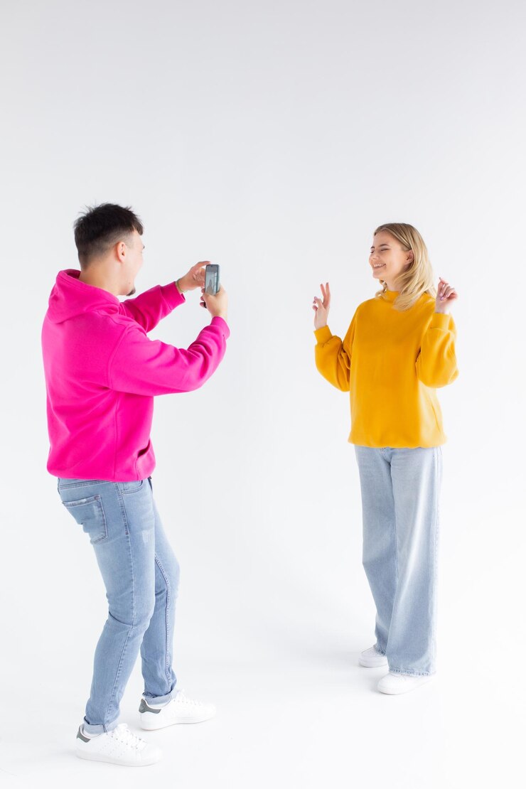 Imagen de un hombre que toma una foto de su mujer positiva y optimista de fondo blanco por teléfono móvil