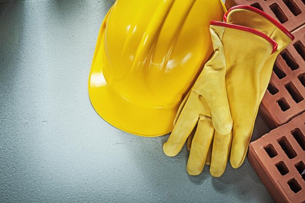 Imagen horizontal de la construcción de ladrillos rojos casco protector guantes de seguridad sobre el concepto de construcción de fondo de hormigón.