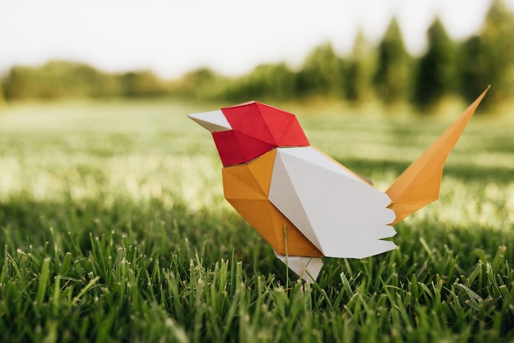 Foto imagen horizontal del primer del pájaro de papel colorido que se coloca en la hierba verde en el parque concepto de ecología y medio ambiente vida silvestre y concepto humano