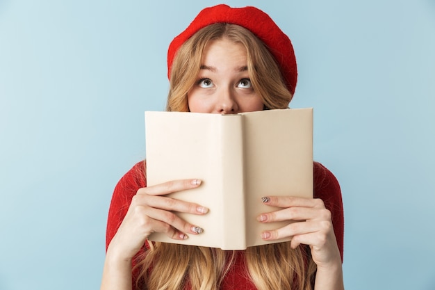 Imagen de la humilde mujer rubia de 20 años vistiendo boina roja libro de lectura aislado