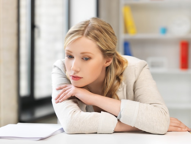 imagen interior de mujer aburrida y cansada detrás de la mesa