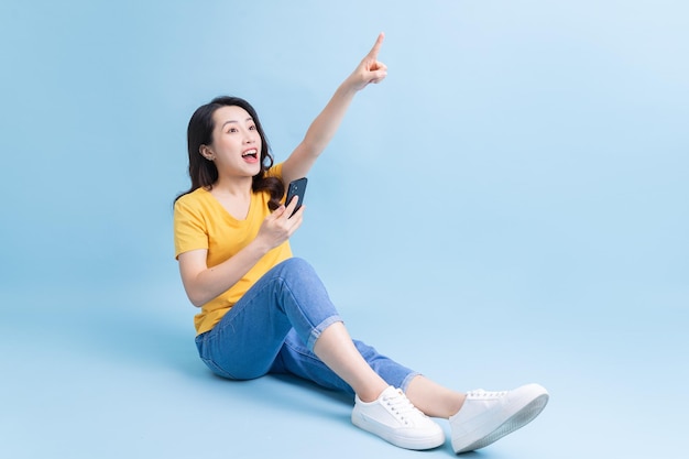 Imagen de una joven asiática sentada y usando un smartphone