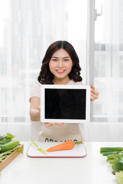 Imagen de joven asiática con tableta en la cocina